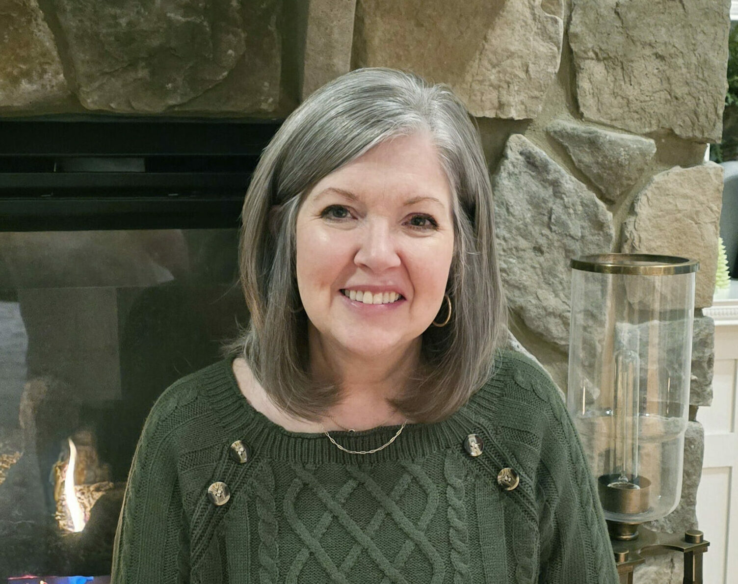 A woman smiling and wearing a green sweater