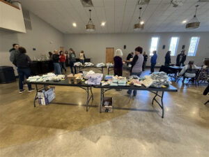 tables with women walking around to pack some bags for donation