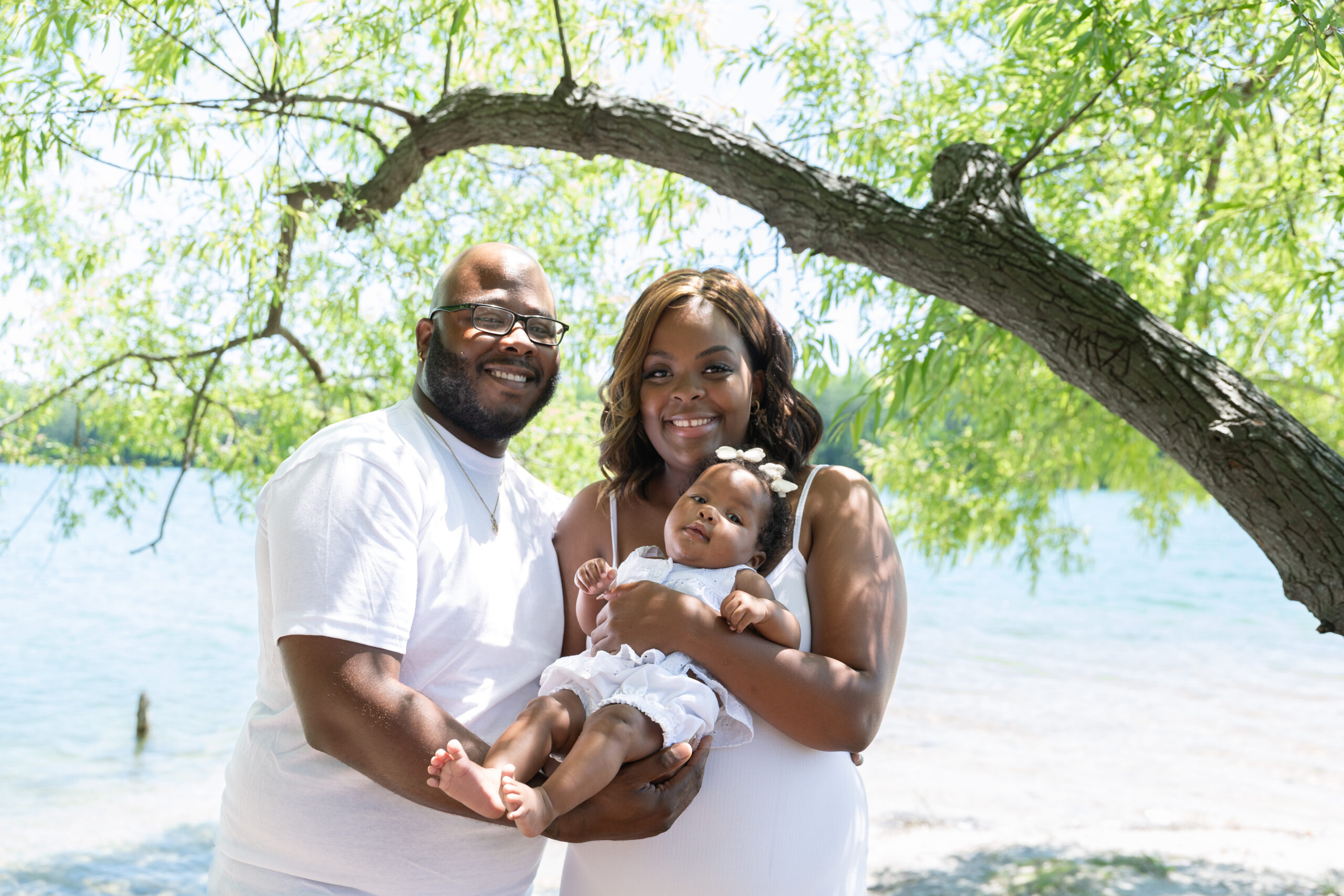 Mom and dad holding their baby under tree